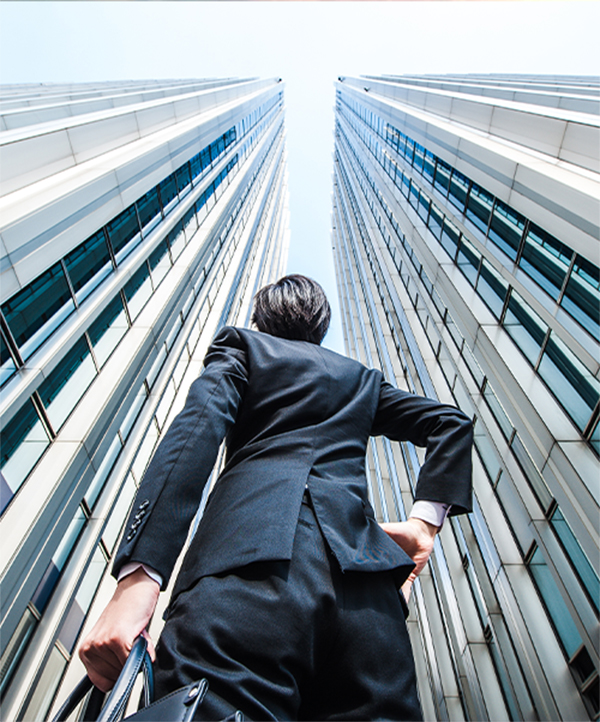 A person staring up between two large skyscrapers